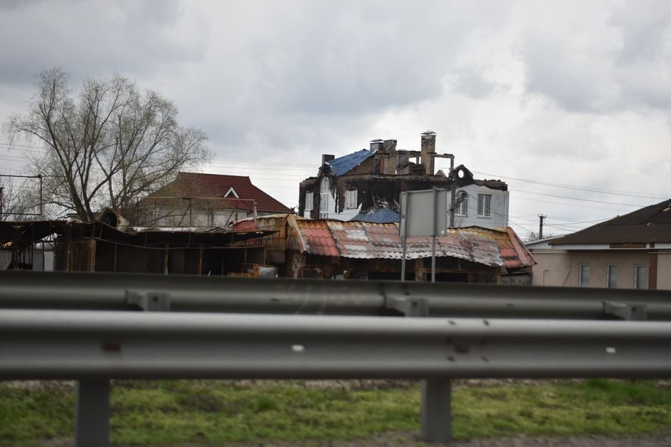 A highway view of fire-damaged residential buildings with cloudy skies.